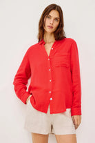 Woman wearing a red button-up shirt and beige shorts on a white background