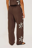 Brown pants with floral appliqués on a white background