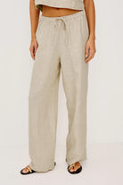 Beige linen pants worn by a person on a white background