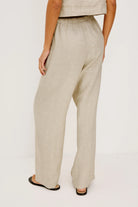 Beige linen pants worn by a person on a white background