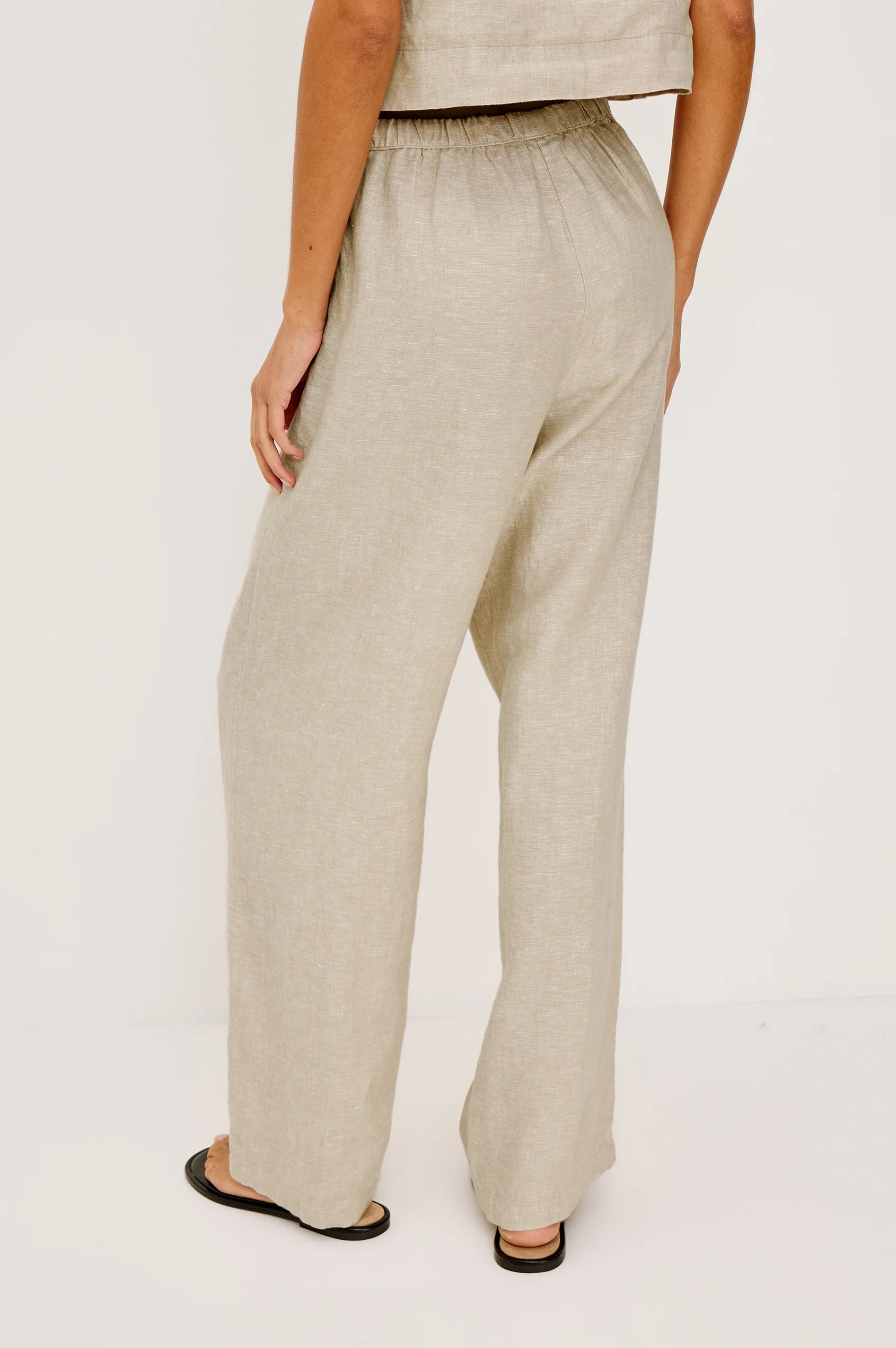 Beige linen pants worn by a person on a white background