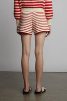 Person wearing a red and white striped sweater and shorts on a plain background