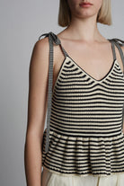 Woman wearing a black and white striped tank top against a plain background