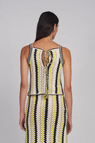 Woman wearing a sleeveless dress with a geometric pattern on a gray background