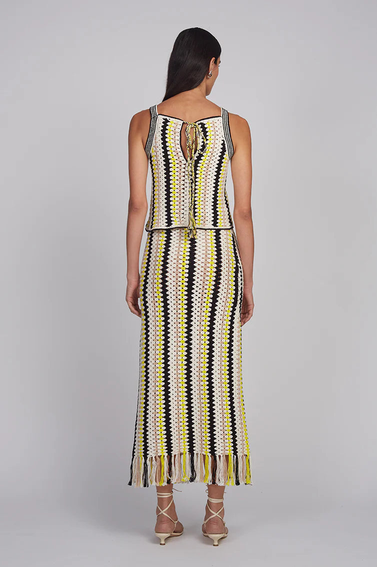 Woman wearing a sleeveless dress with a geometric pattern on a gray background