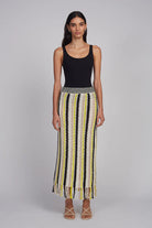 Woman wearing a black tank top and a patterned skirt on a gray background