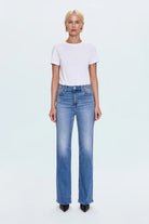 Person wearing a white t-shirt and blue jeans on a light gray background