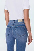 Person wearing blue jeans with a visible brand label on a white background