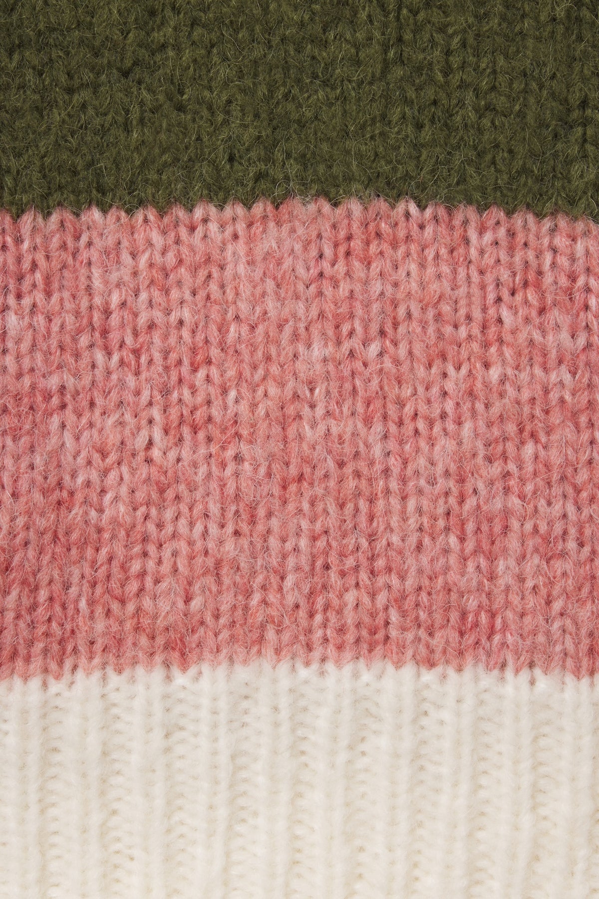 Close-up of a knitted textile with horizontal color blocks: dark olive green at the top, heathered dusty pink in the middle, and off-white at the bottom.