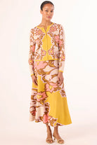 Woman wearing a floral dress with a yellow top and skirt on a white background