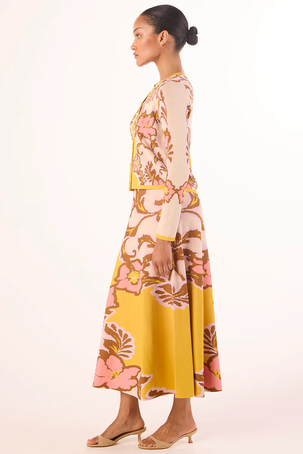 Woman wearing a floral dress with a yellow skirt on a white background