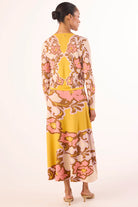 Woman wearing a floral dress with a yellow top and pink skirt on a white background