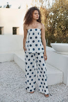 Woman wearing a polka dot strapless top and wide-leg pants outdoors.