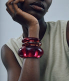 Person wearing a beige sleeveless top with a close-up of their arm and hand adorned with red bangles.