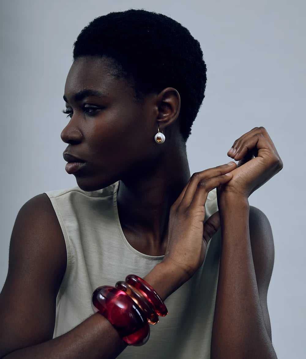 Woman wearing a red bracelet on a gray background