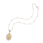 Gold necklace with a shield-shaped pendant on a white background