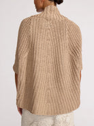 Beige knitted poncho worn by a person on a white background