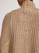 Close-up of a beige knitted sweater with a plain background