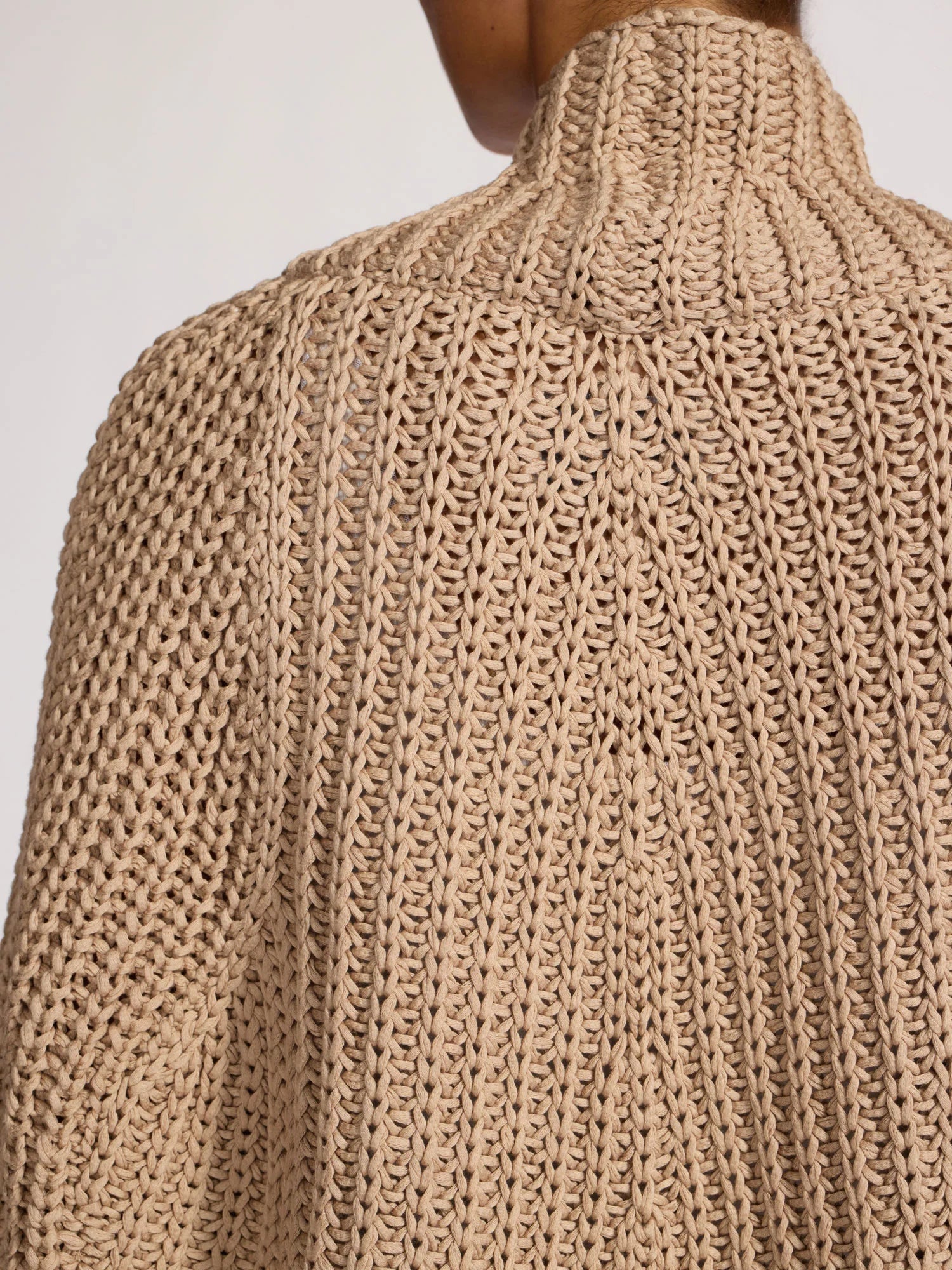 Close-up of a beige knitted sweater with a plain background