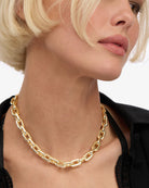 Gold chain necklace worn by a model on a white background