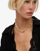 Woman wearing a gold chain necklace against a white background