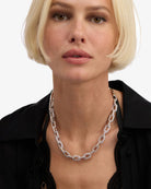 Woman wearing a silver chain necklace against a white background