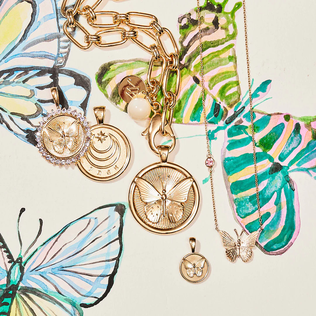 Gold butterfly-themed jewelry on a decorative background with colorful butterflies.