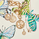 Gold butterfly-themed jewelry on a decorative background with colorful butterflies.