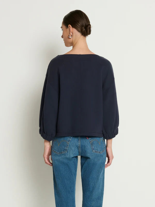 Person wearing a navy sweater and blue jeans against a white background