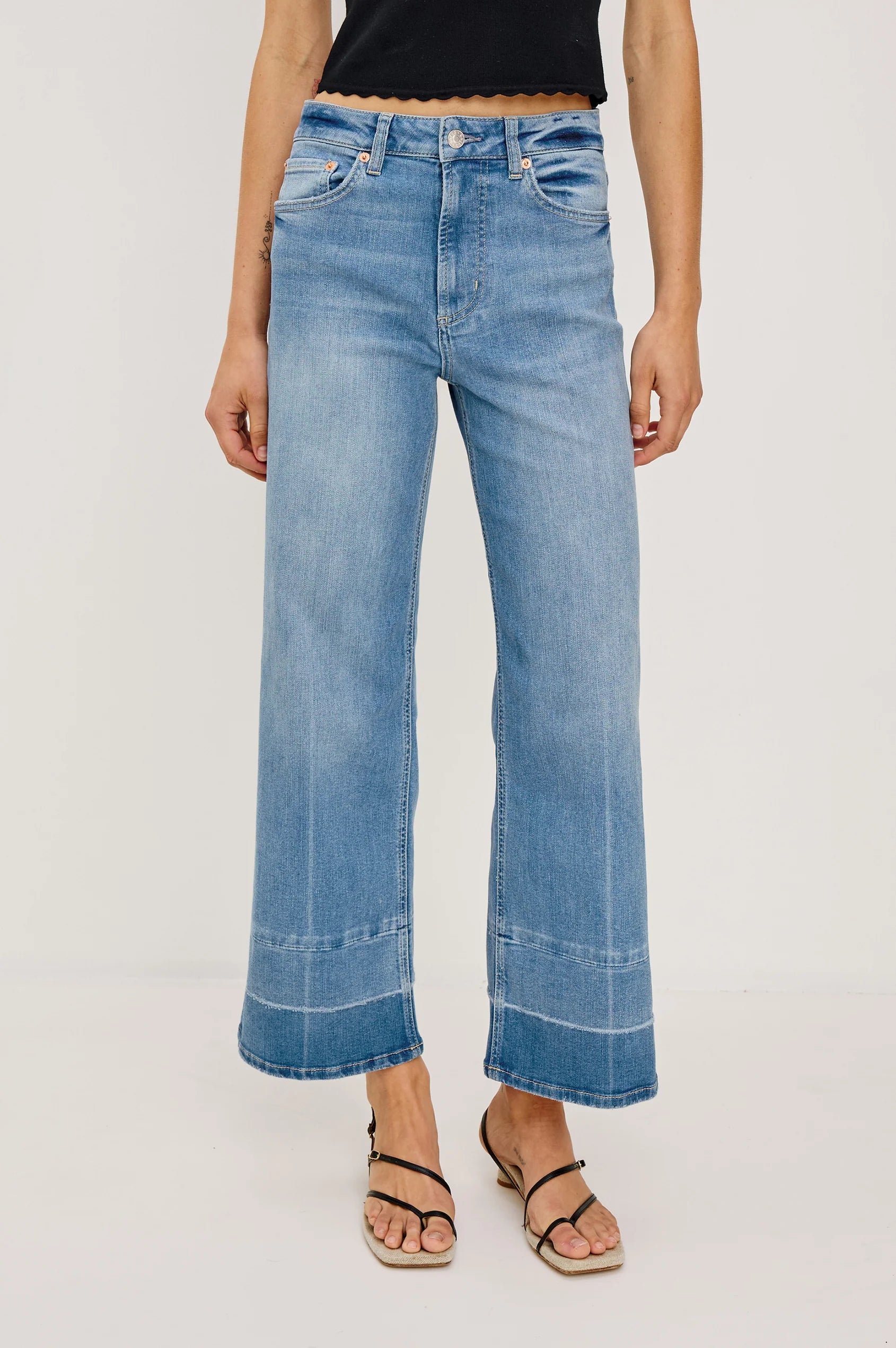 Person wearing blue jeans on a plain background