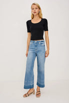 Woman wearing a black top and blue jeans on a white background
