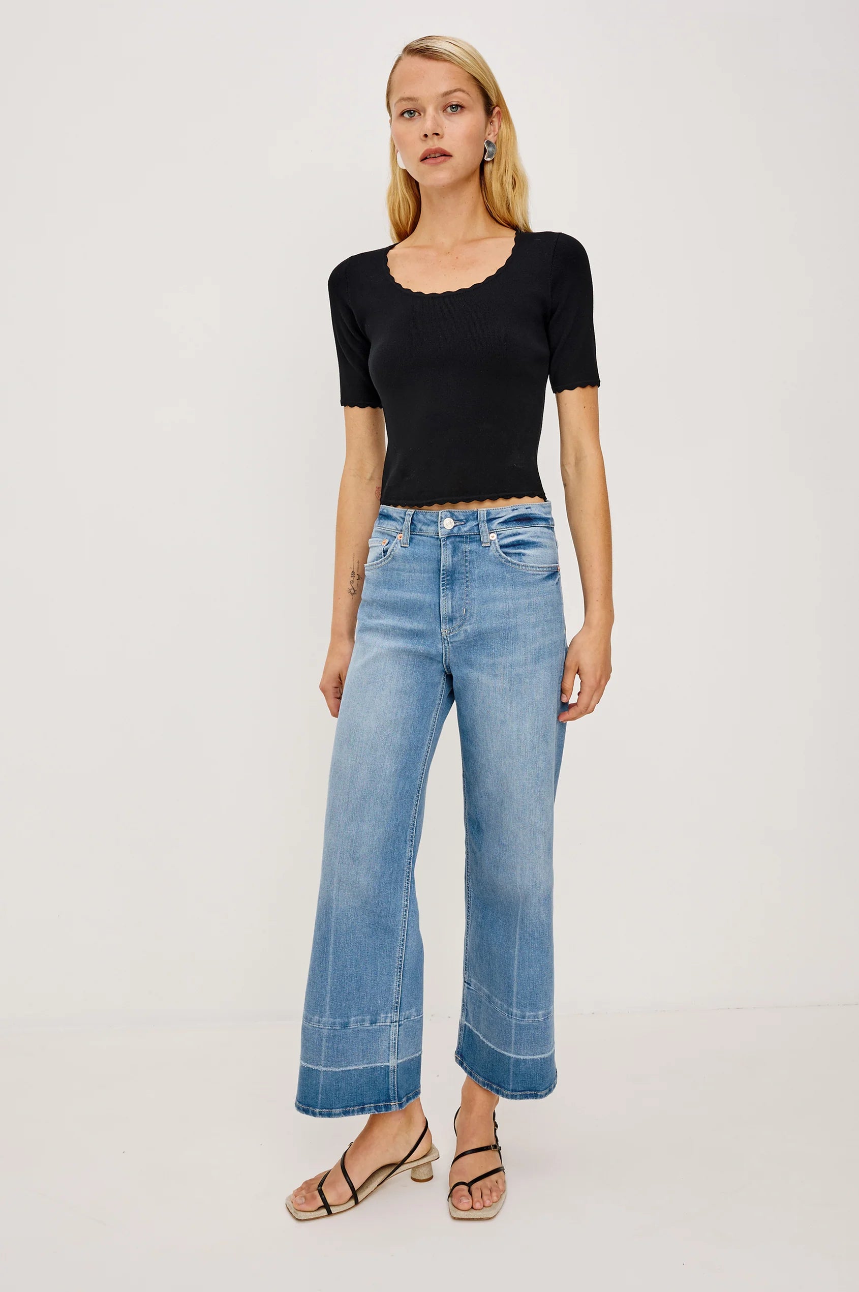 Woman wearing a black top and blue jeans on a white background
