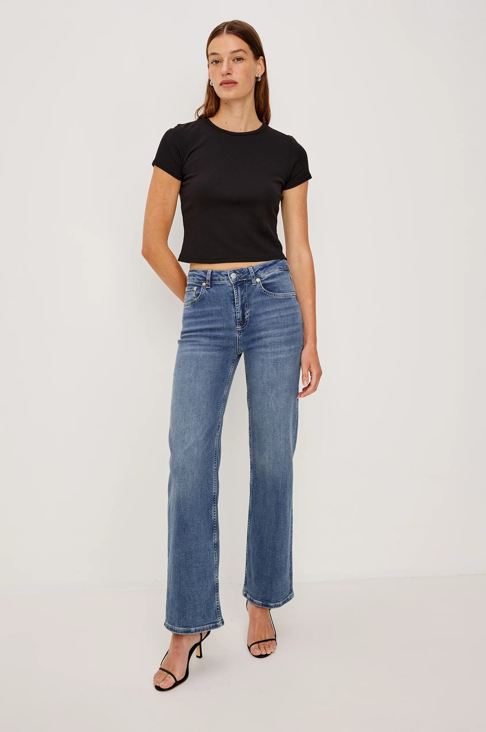 Woman wearing a black t-shirt and blue jeans on a white background