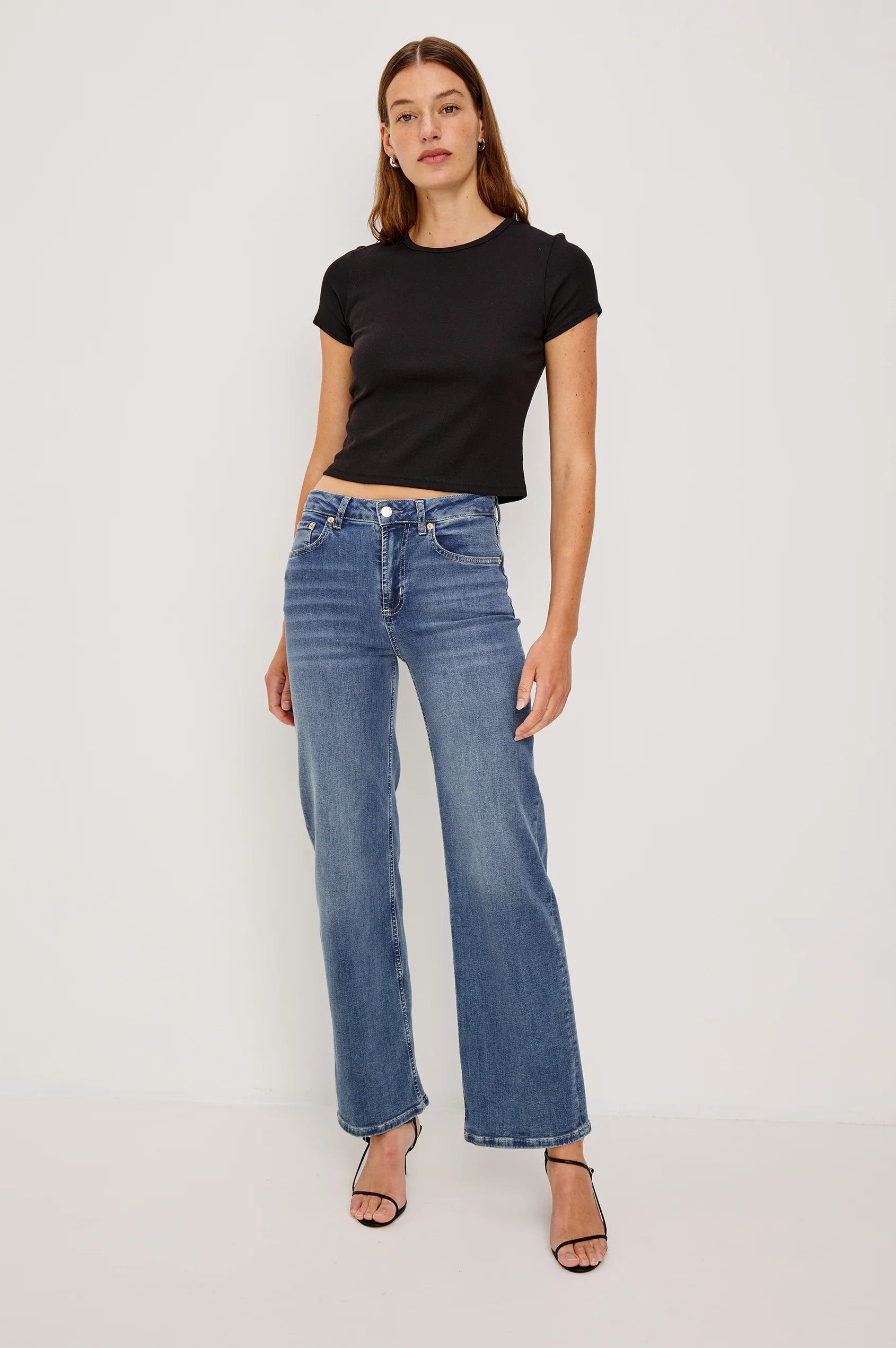 Woman wearing a black t-shirt and blue jeans on a white background