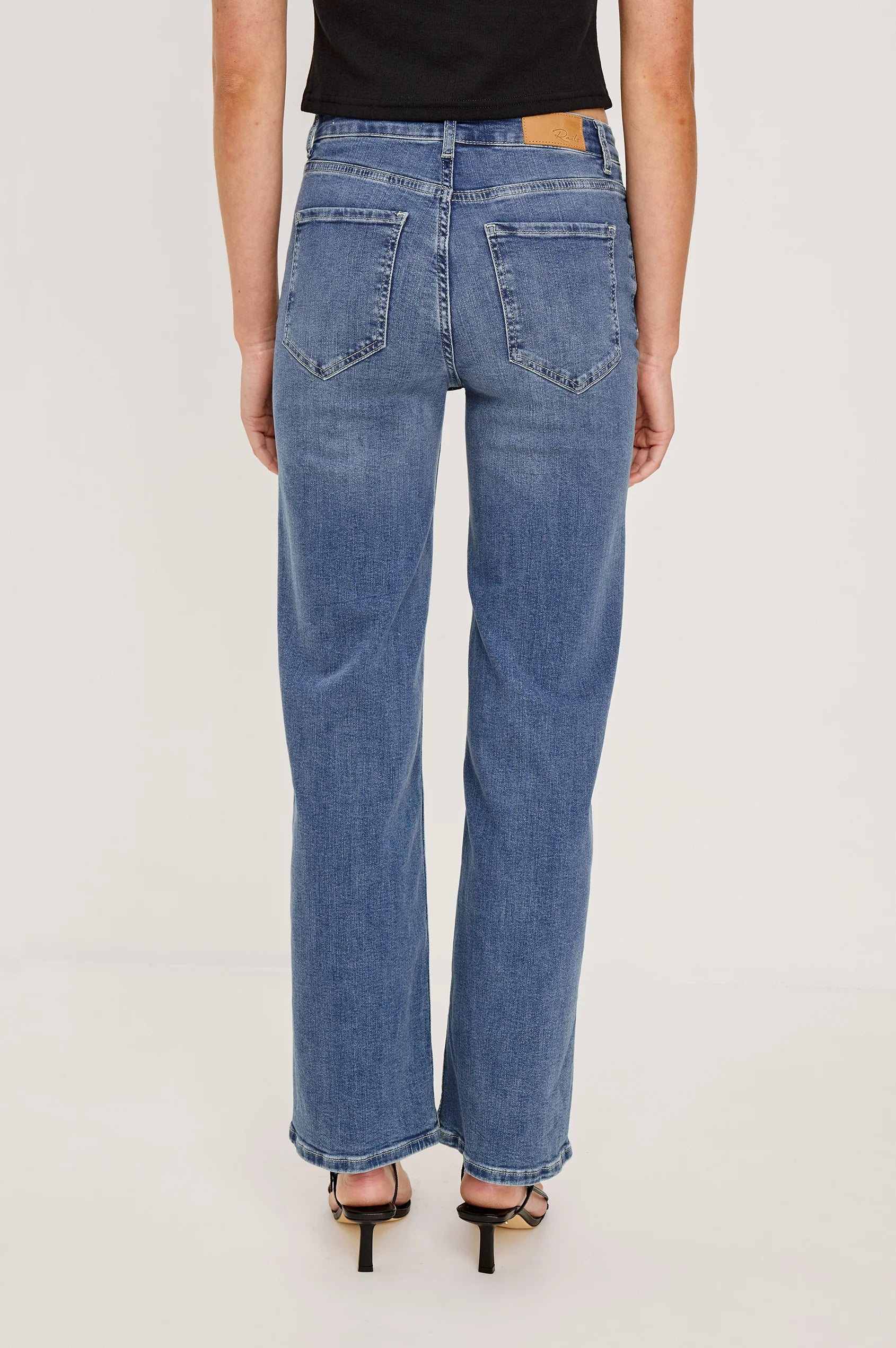 Person wearing blue jeans on a plain background