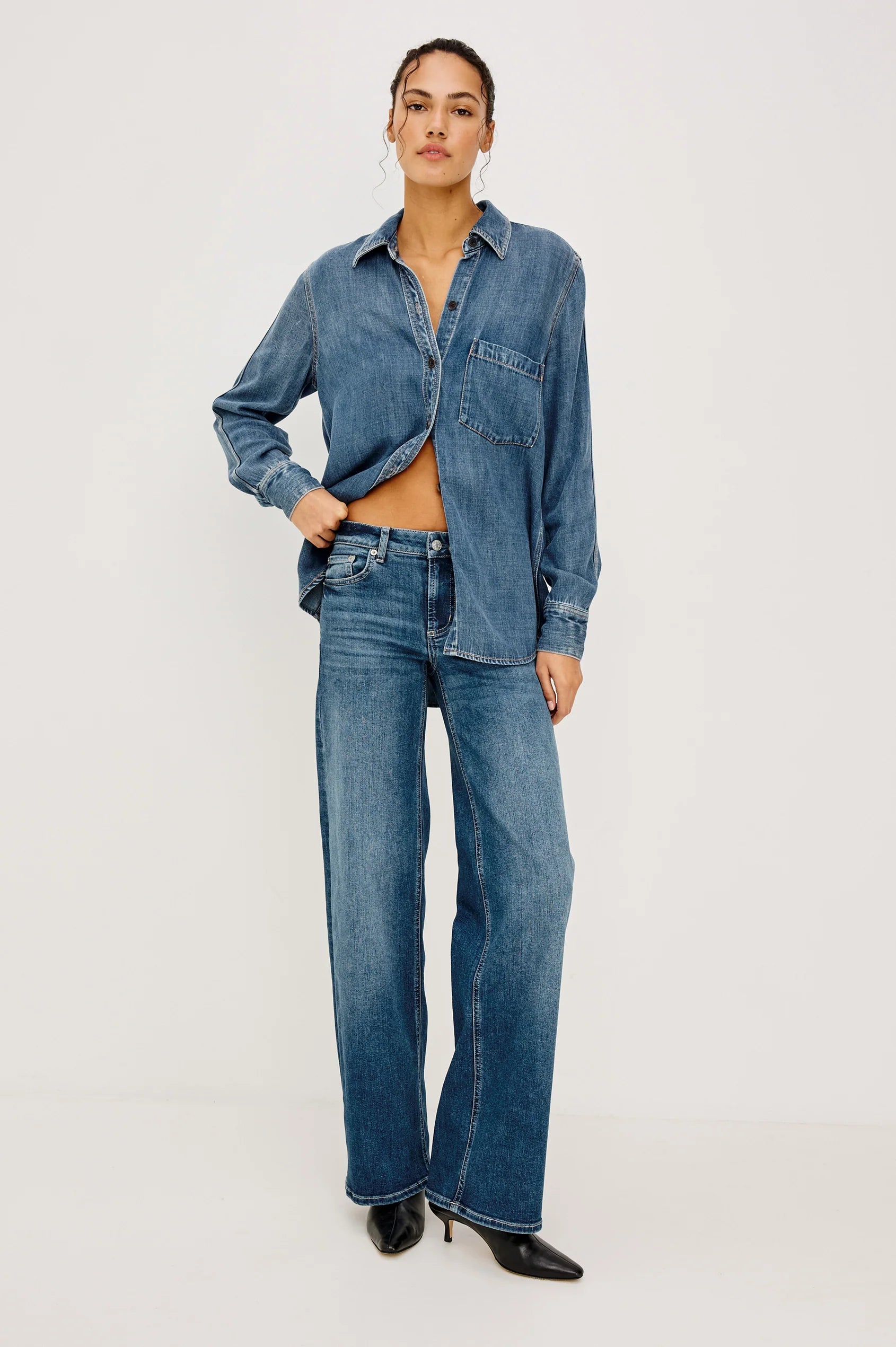 Person wearing a blue denim shirt and jeans on a white background