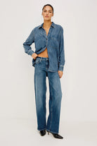 Person wearing a blue denim shirt and jeans on a white background