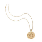 Gold necklace with a round pendant on a white background