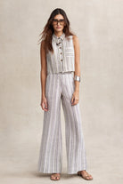 Woman wearing a striped sleeveless top and wide-leg pants on a beige background