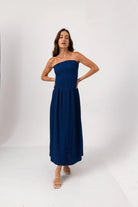 Woman wearing a strapless navy dress on a white background