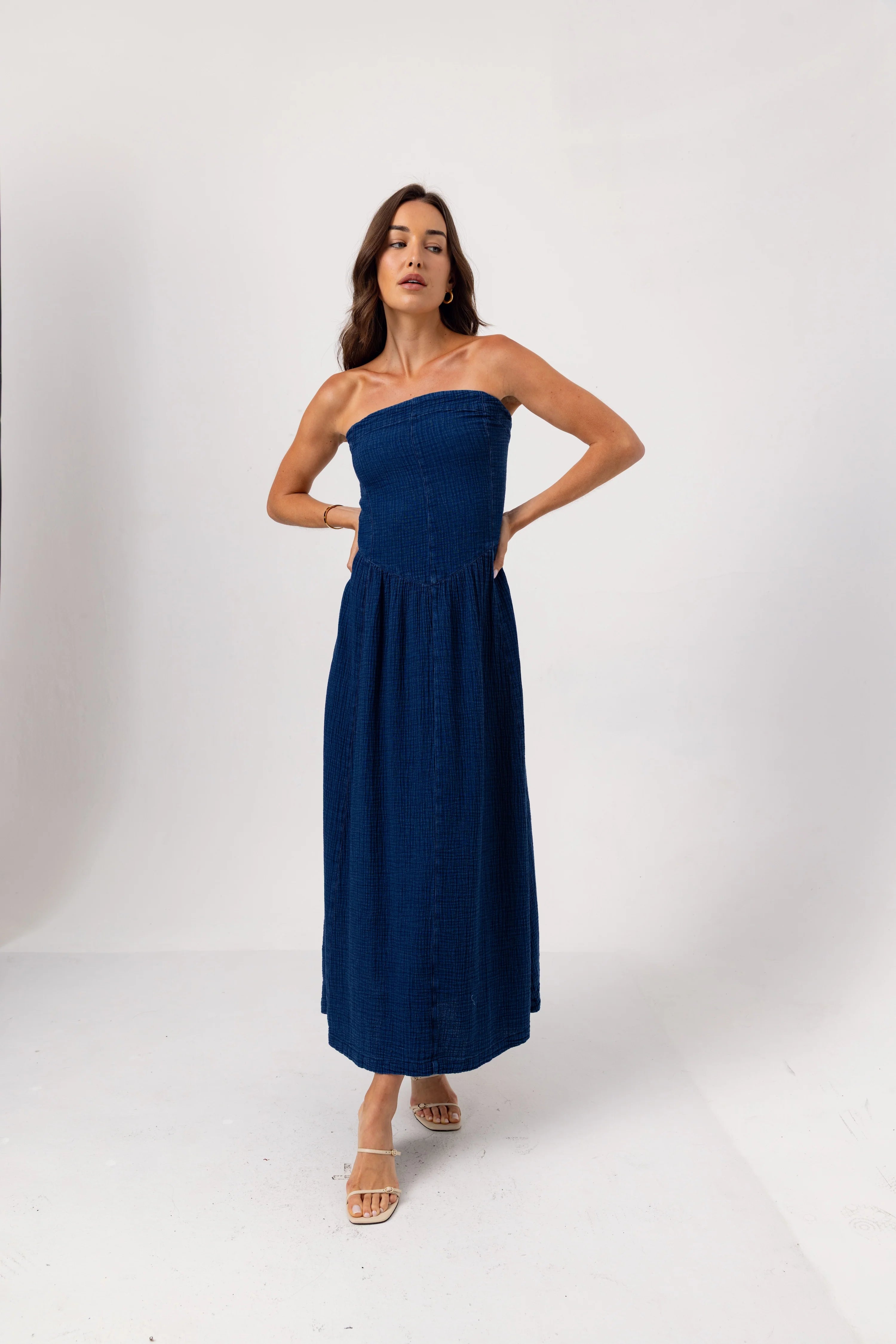 Woman wearing a strapless navy dress on a white background