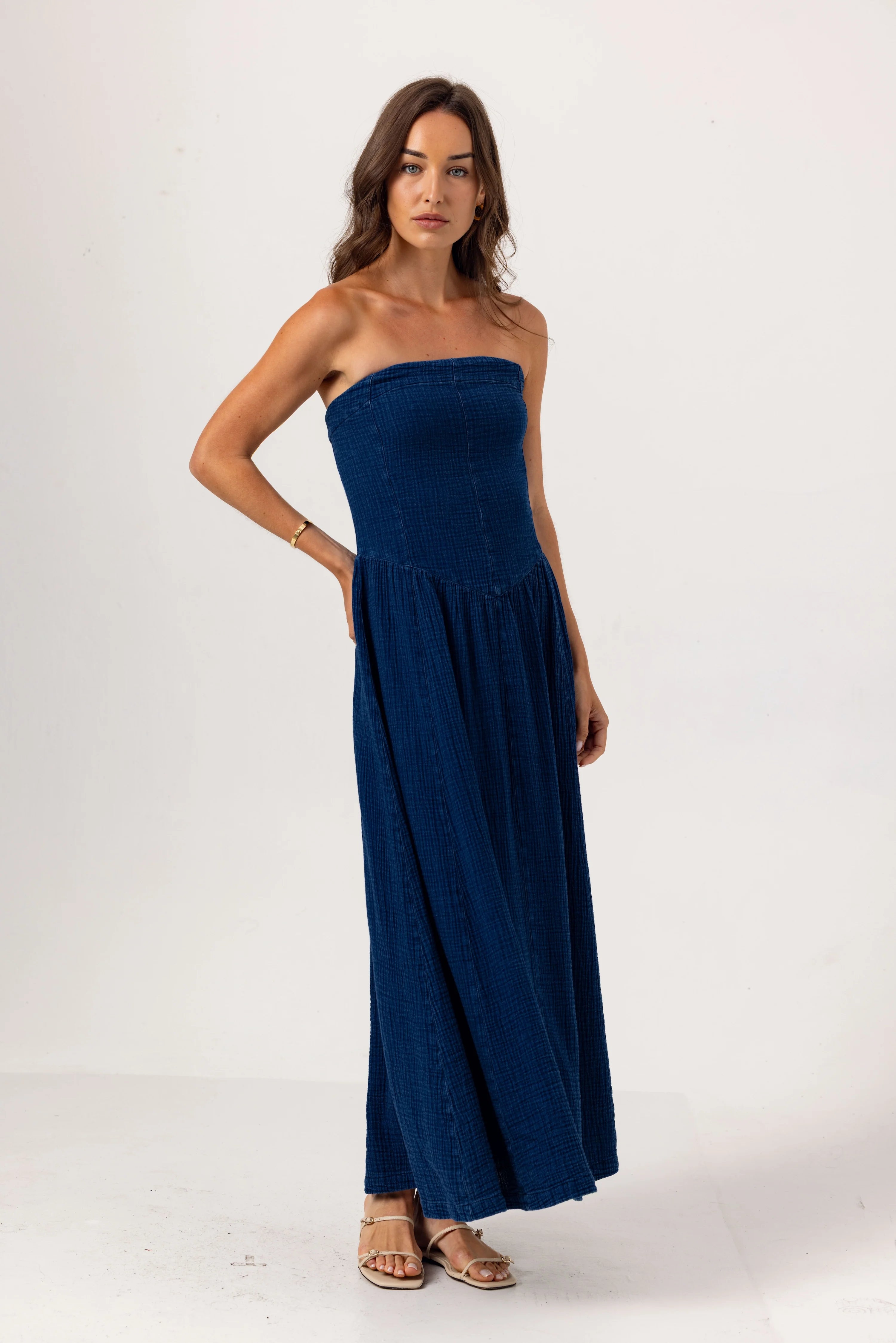 Woman wearing a strapless navy blue dress on a white background