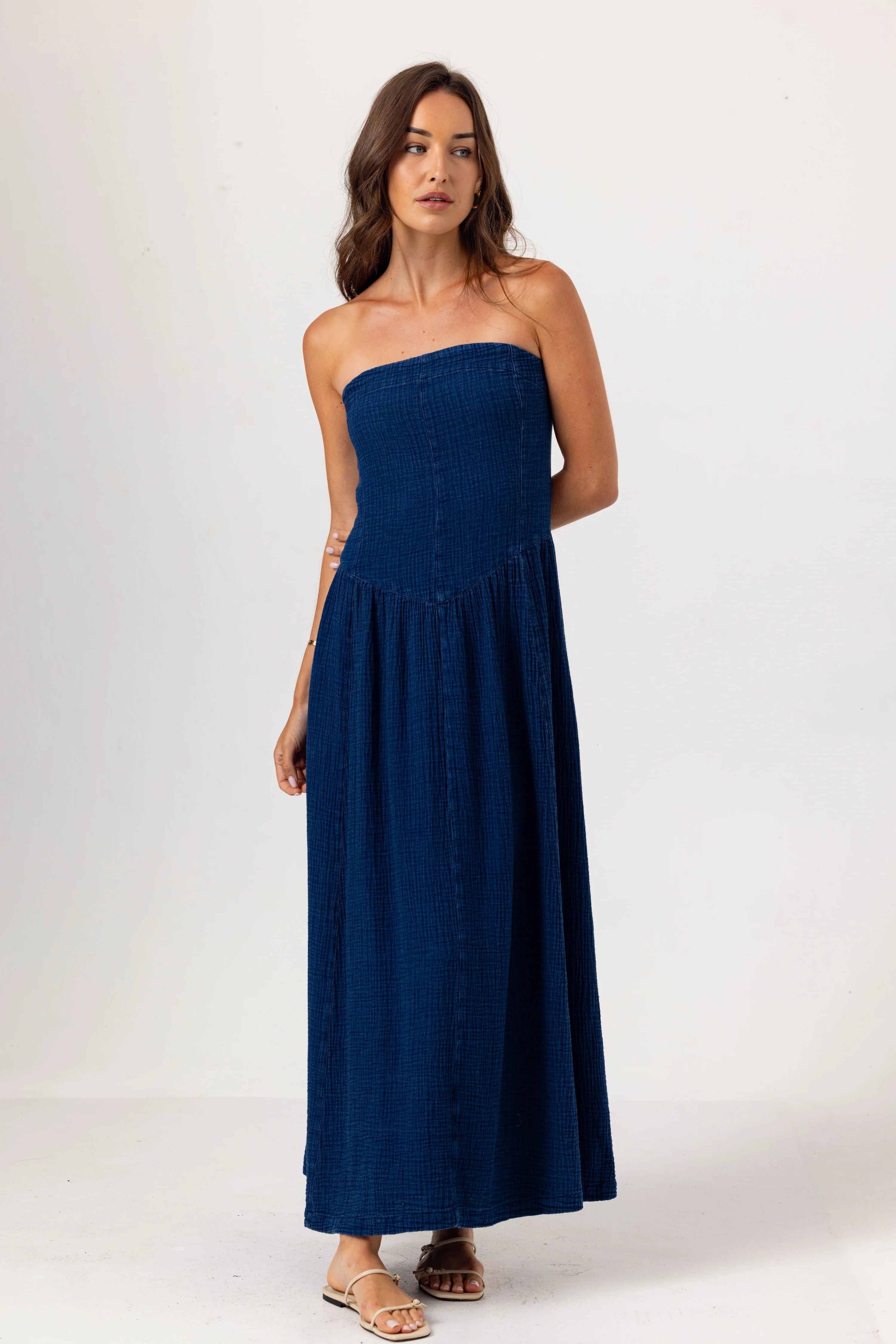 Woman wearing a strapless navy blue dress on a white background