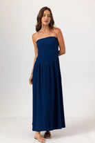 Woman wearing a strapless navy blue dress on a white background