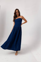Woman wearing a strapless navy blue dress on a white background