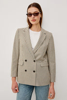 Person wearing a checkered blazer and sunglasses against a white background