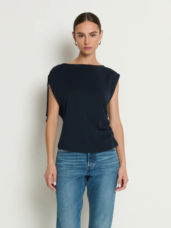 Woman wearing a black top and blue jeans against a white background