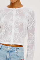 White lace long-sleeve top worn by a person on a white background