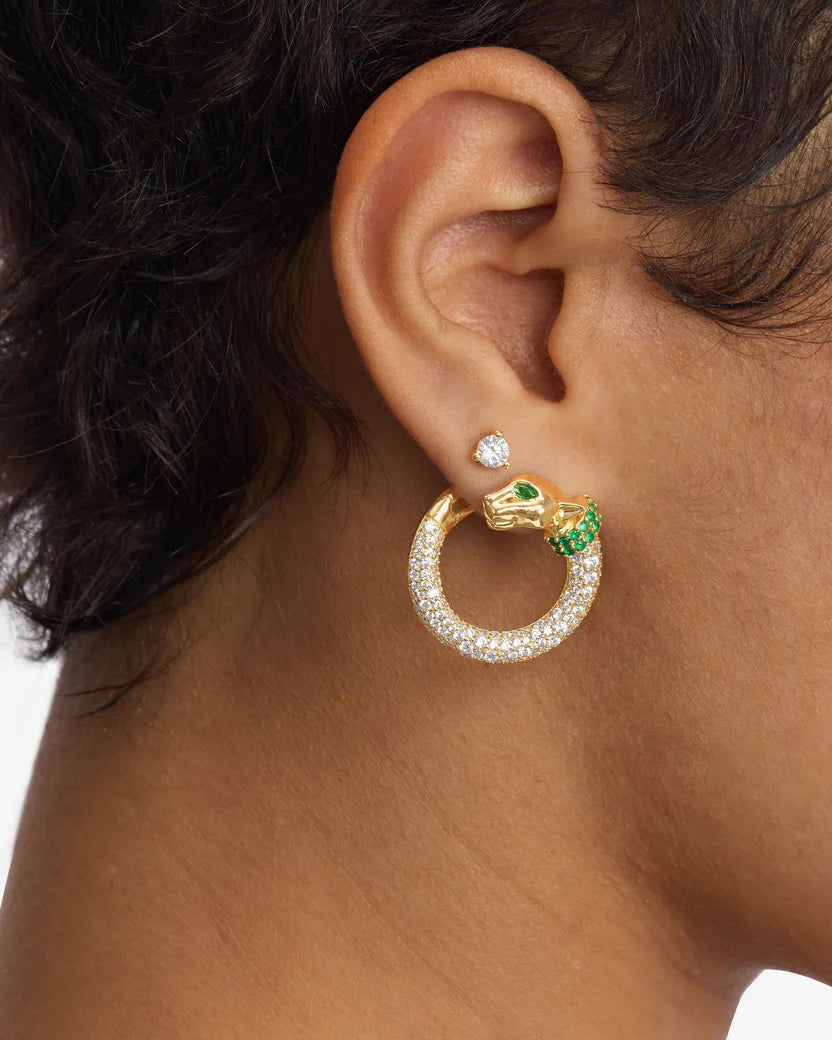 Gold hoop earring with green gemstone worn by a person