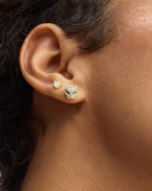 Close-up of an ear wearing two diamond stud earrings.